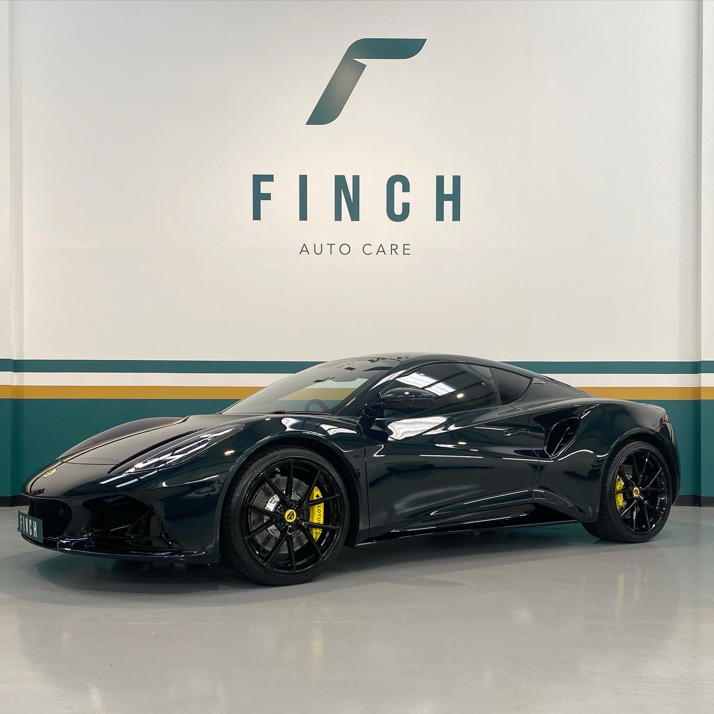 A black sports car parked in front of the finch auto care sign.