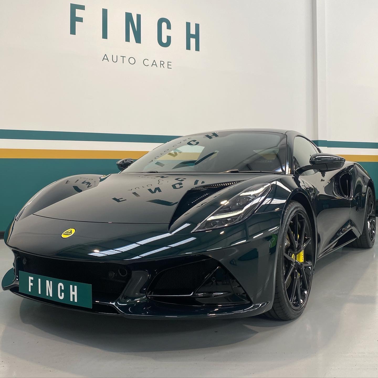 Black sports car parked inside a modern auto care shop.