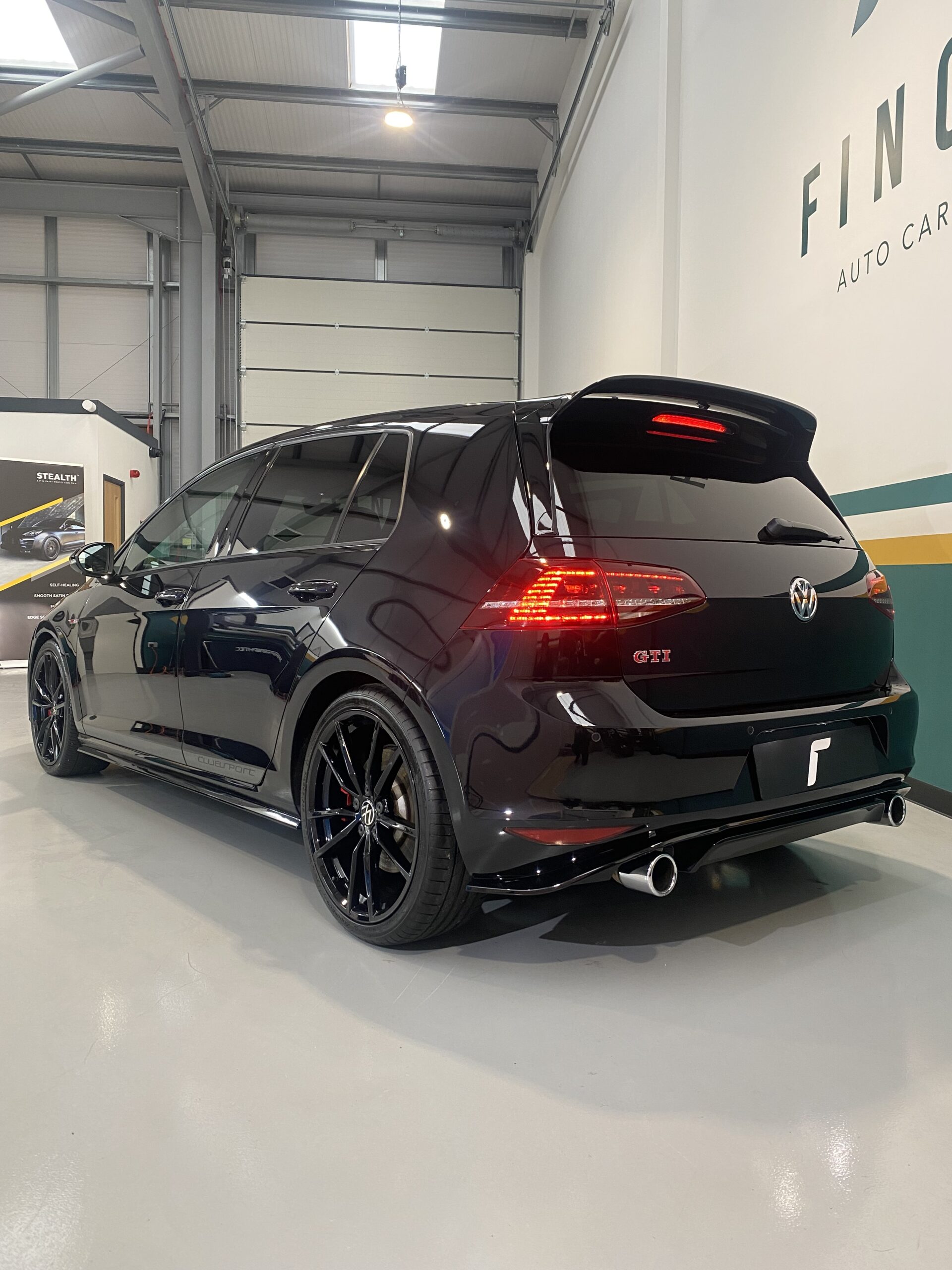 Black volkswagen golf gti parked in a showroom with trunk open.