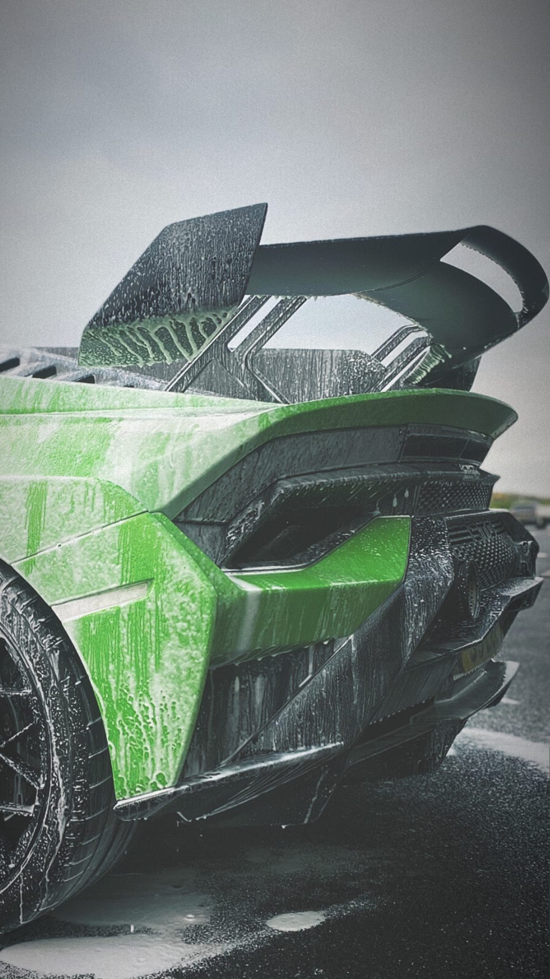 Green sports car with aerodynamic design elements, wet from the rain.