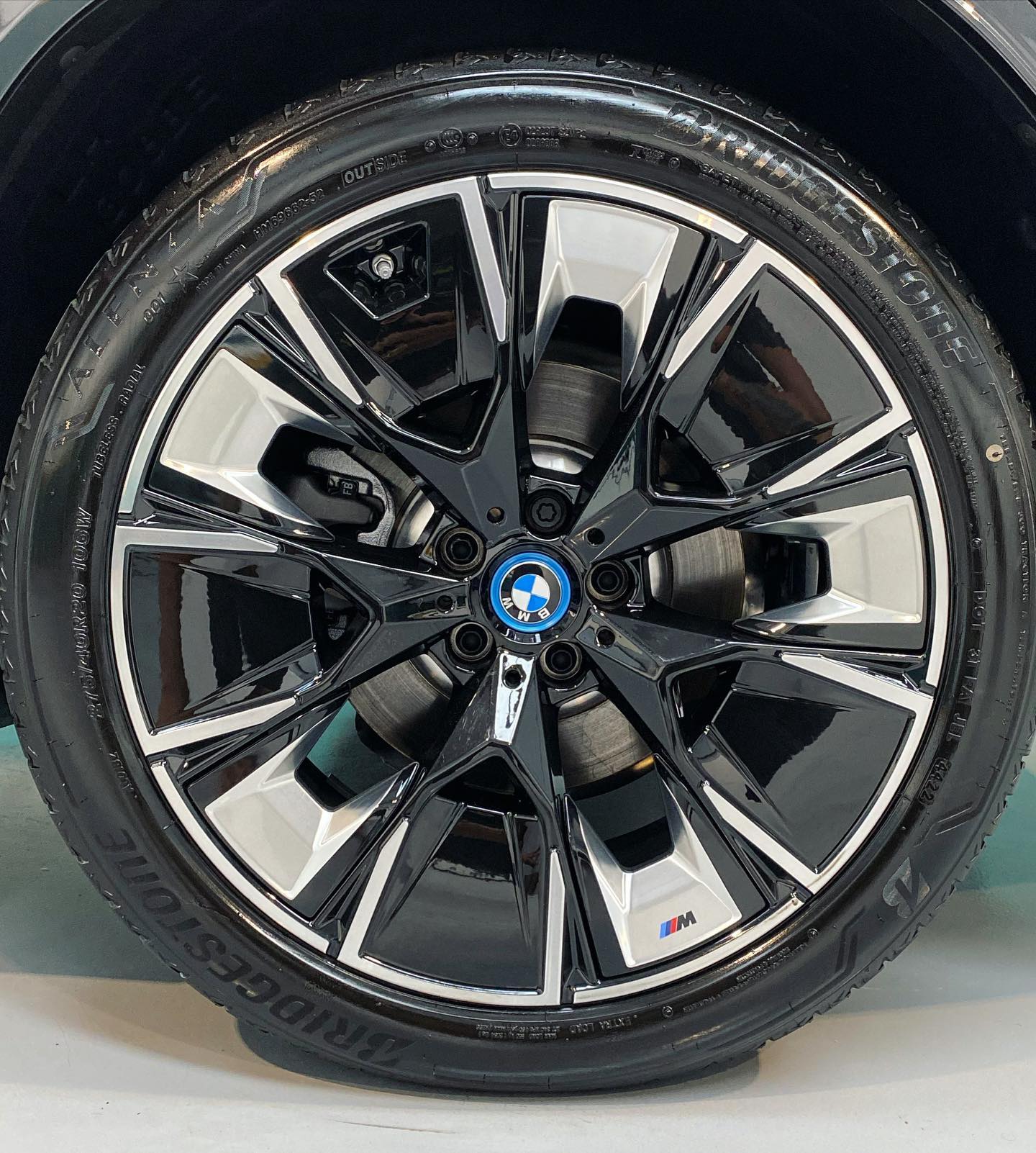 Close-up of a bmw wheel with a black and silver rim, featuring the bmw logo and an m badge.