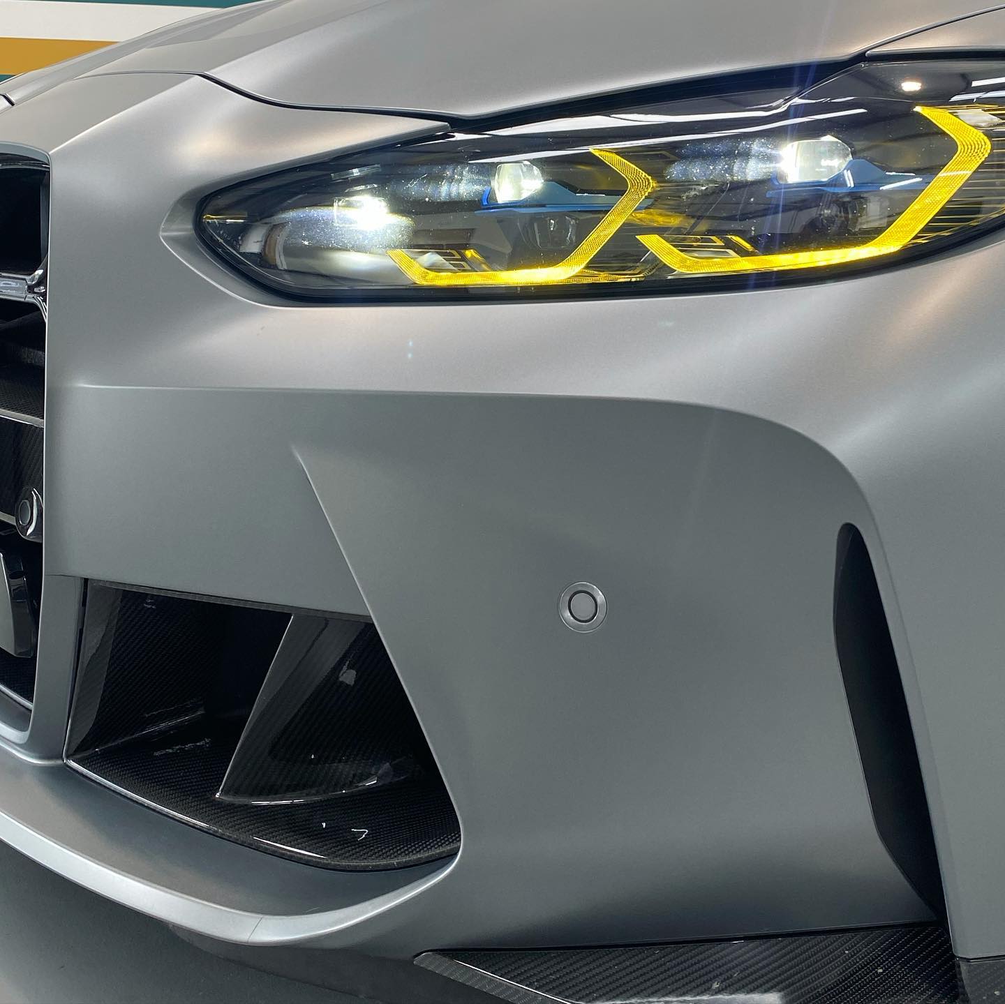 Close-up of a gray sports car's front showcasing its headlight and air intake design.