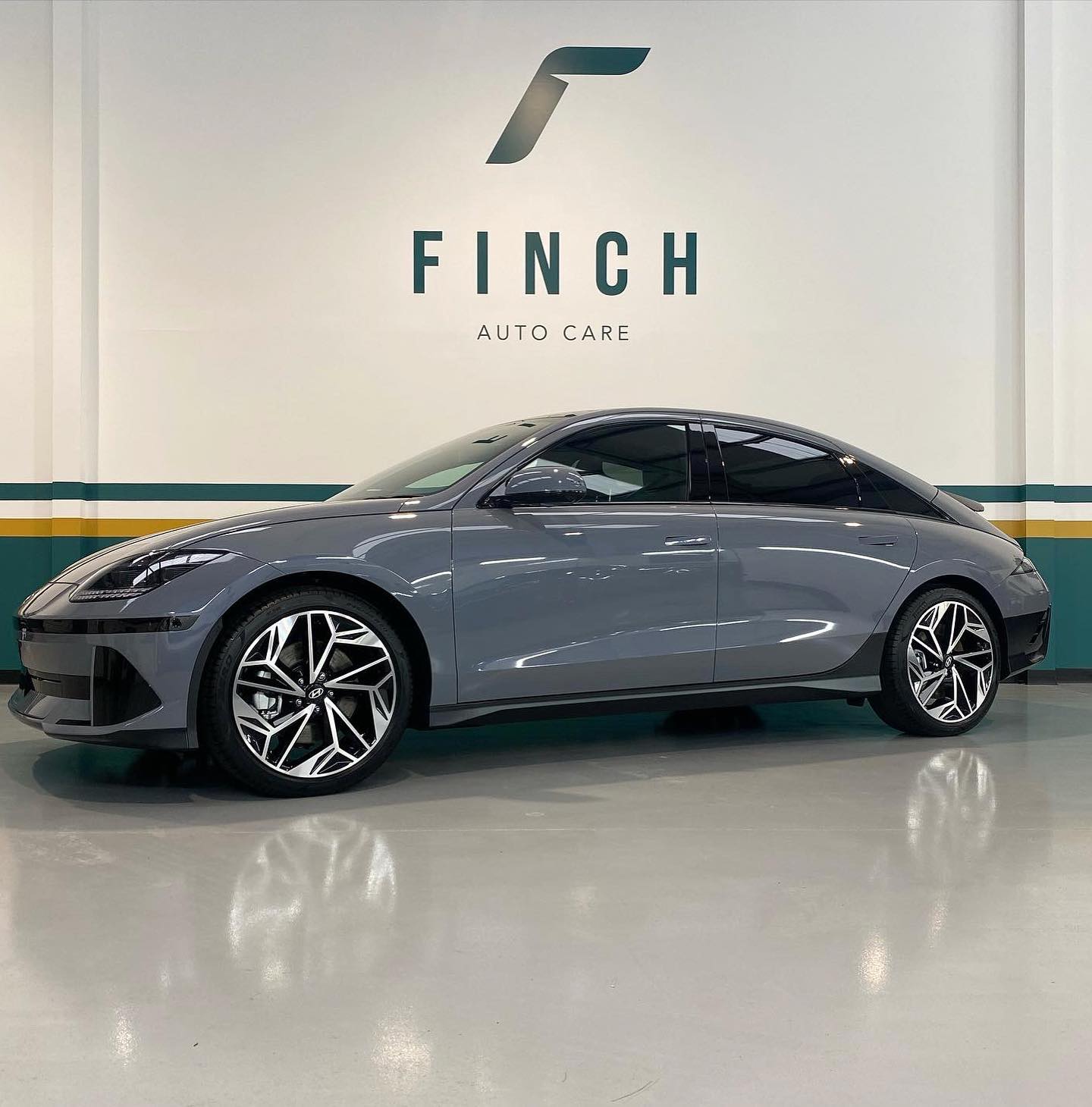 A sleek electric vehicle displayed in a showroom with finch auto care branding in the background.