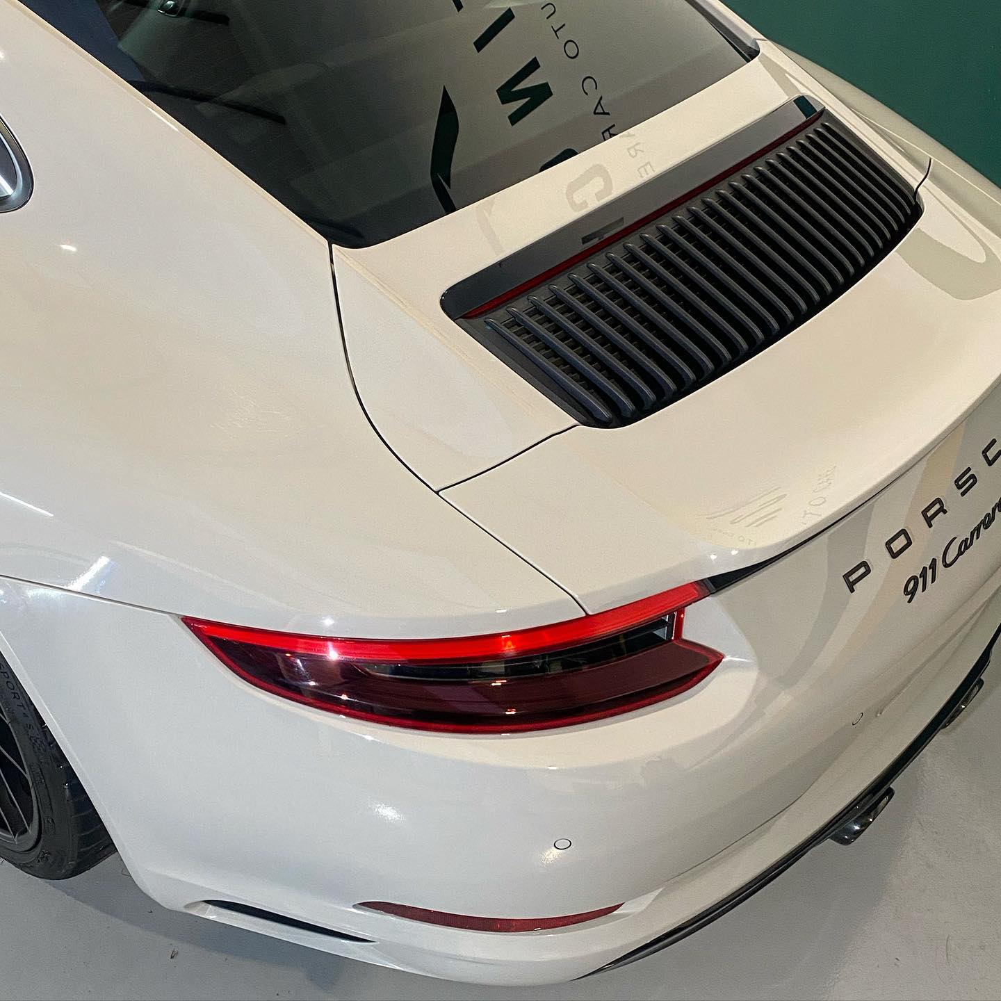 Rear view of a white porsche 911 carrera showing the taillights and model designation.