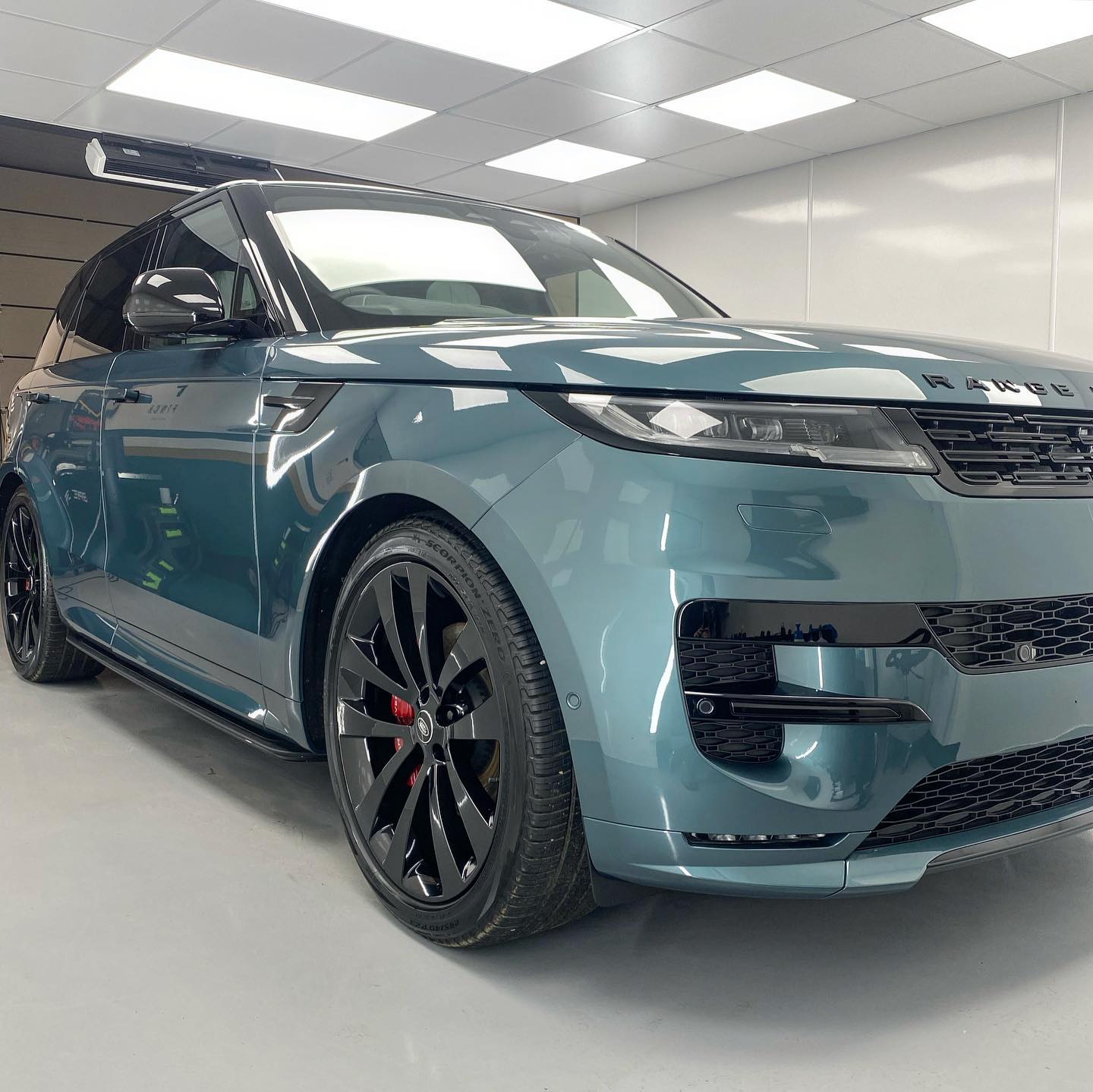 A blue range rover sport with black wheels parked indoors.